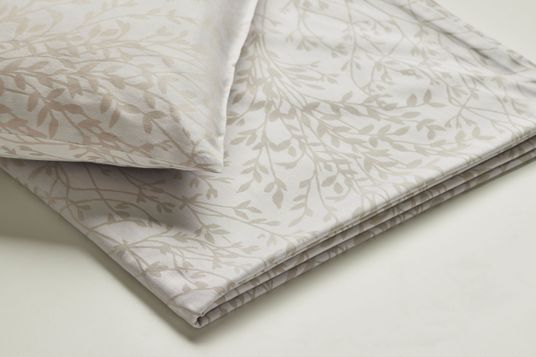 Kissenbezug und Decke mit feinem, beigem Blätter-Design auf hellem Grund